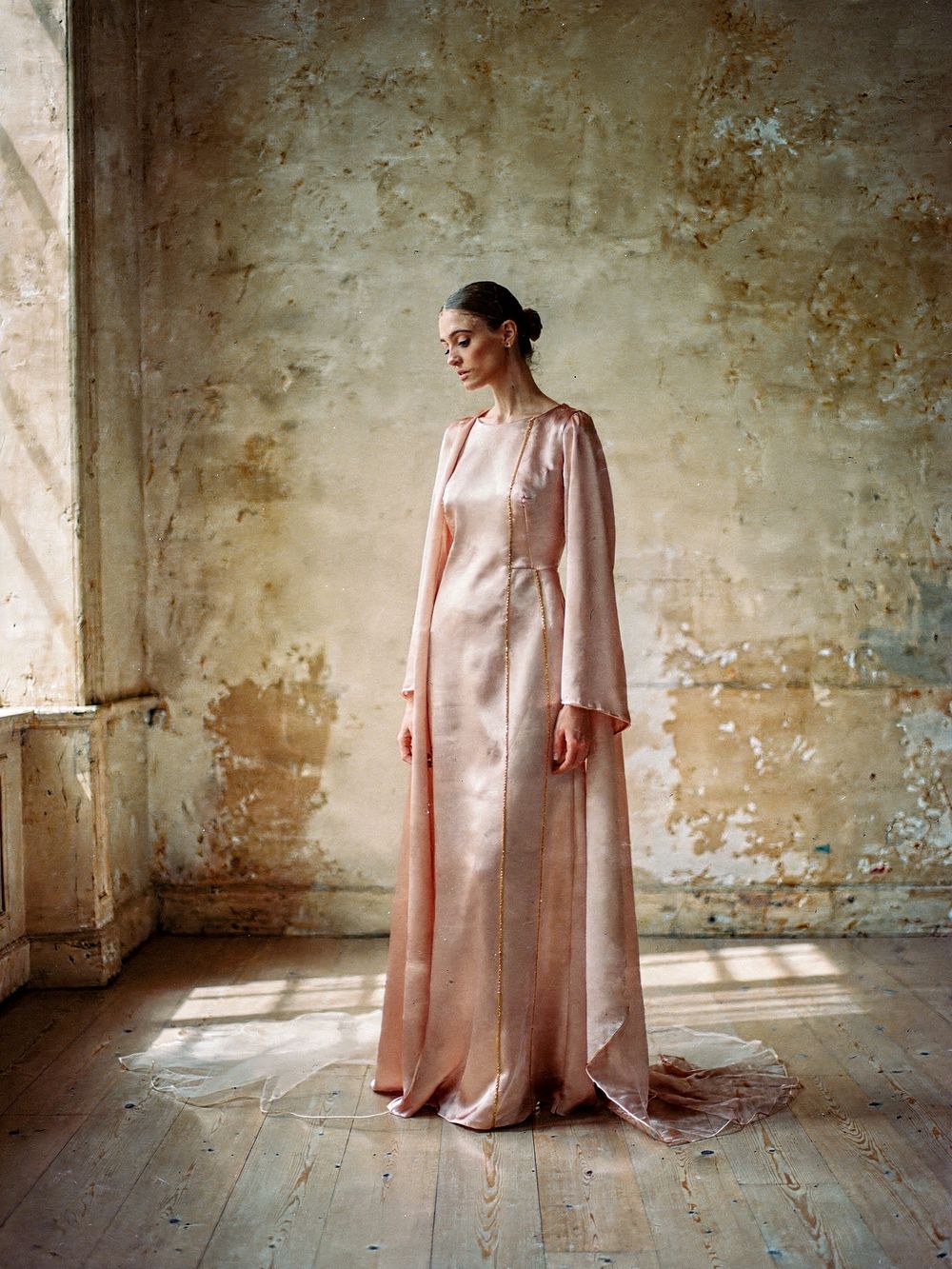 Look 03, La Soie: a blush silk gown with long draped sleeves and gold-thread seams, gaze lowered
